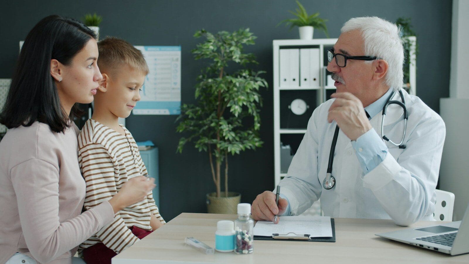 Doctor talking to mother and child at desk